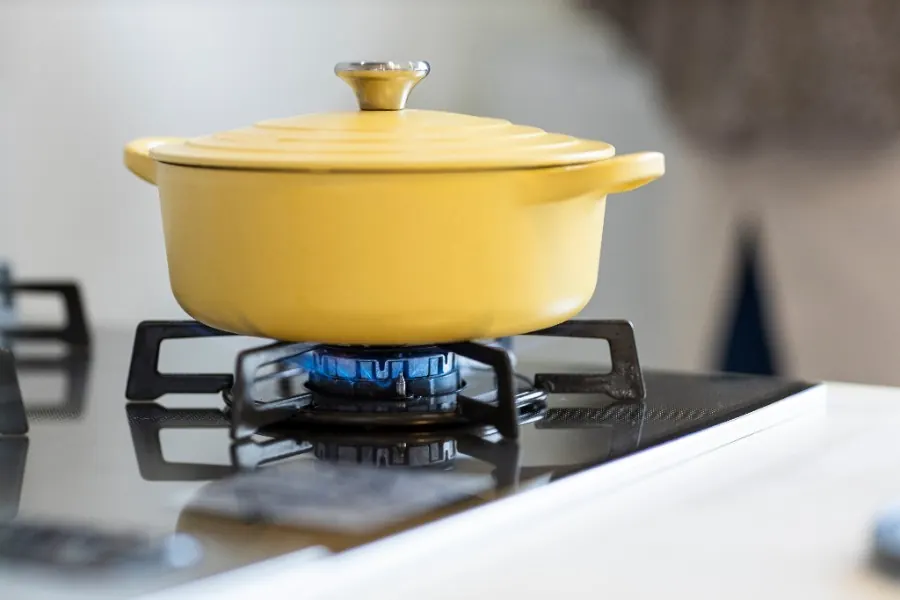 Cocotte jaune sur une gazinière allumée, installation contrôlée lors du diagnostic gaz