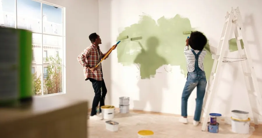Couple repeignant un mur intérieur, anciennes peintures analysées lors du diagnostic plomb